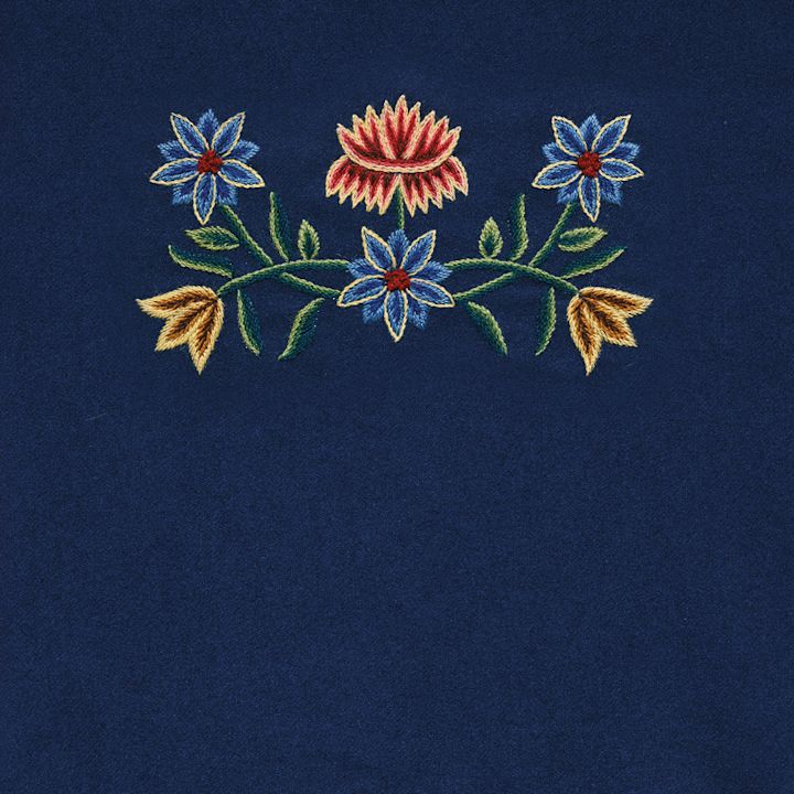 Tradisjonelt broderi på mørkeblå bakgrunn med blå, røde og gule blomster forbundet av grønne stilker og blader.