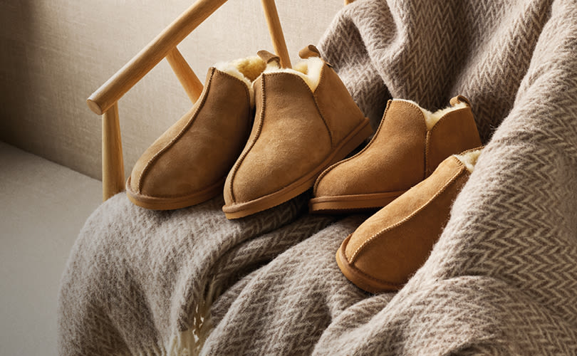 To par lysebrune semsket skinnsko med ullfor plassert på et grått ullpledd i en stol med treramme.