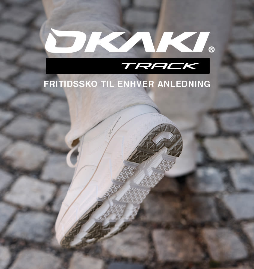 Hvite OKAKI Track fritidssko med mønstret såle på brosteinsunderlag. Logo og teksten "FRITIDSSKO TIL ENHVER ANLEDNING" vises.