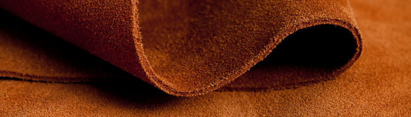 Närbild av ett brunt mockaskinn som delvis är rullat på en plan yta.