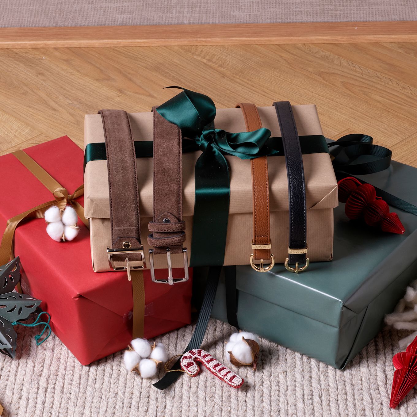 Presentförpackningar i rött, beige och grönt med läderbälten i brunt och svart, dekorerade med grönt sidenband.