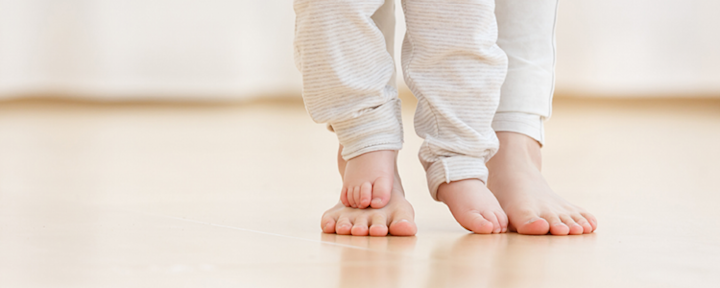 Barnfötter trampar på vuxenfötter.