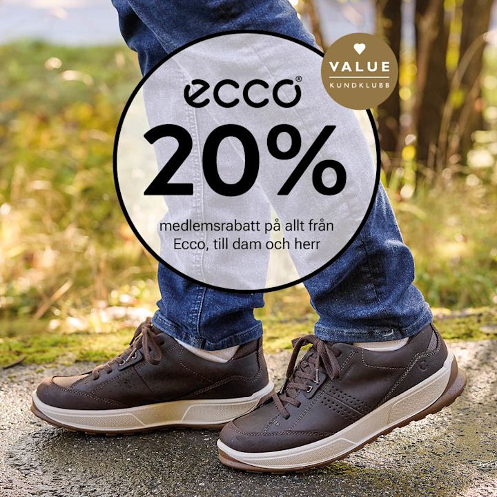 Mörkbruna Ecco sneakers i läder med vita sulor och snörning, på en person i jeans utomhus.
