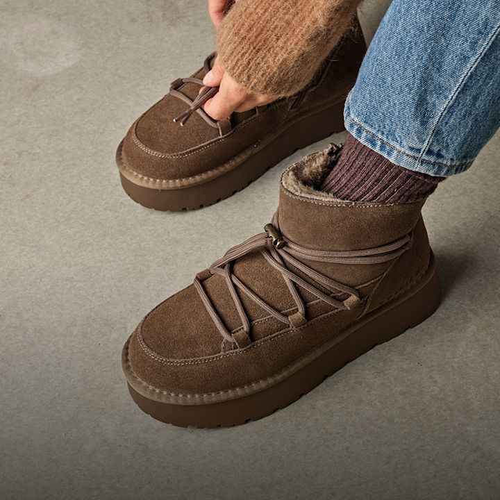Brune semsket vinter-ankelboots med snøring og pelsfôr, stylet med jeans og brune sokker.