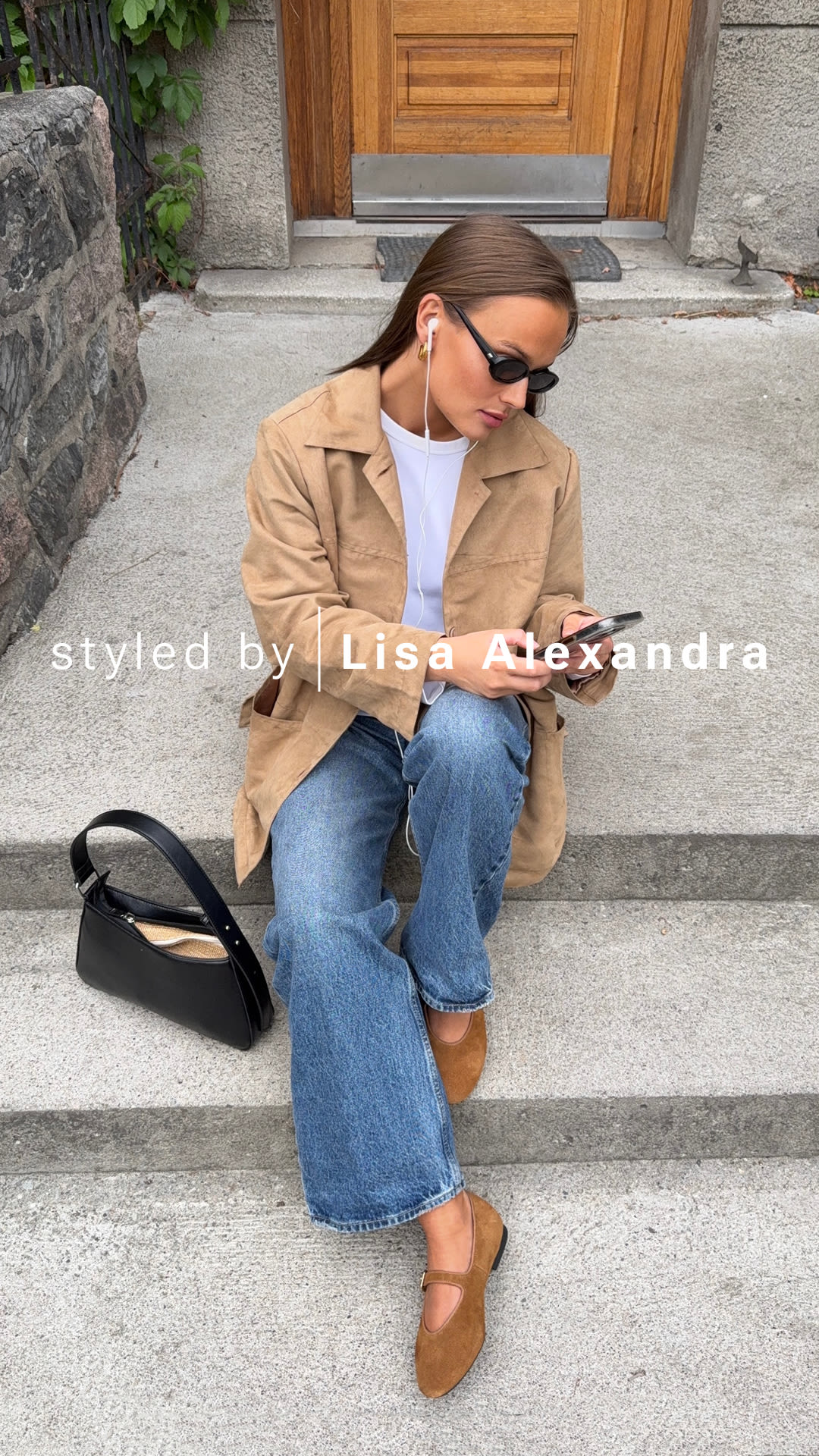 Person i beige kavaj och jeans sitter på trappa med bruna mockaballerinaskor från Unified och svart väska bredvid sig.