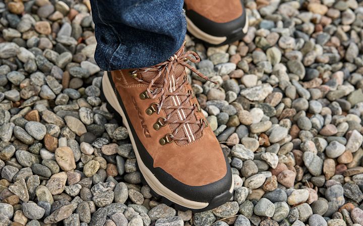 Brune tursko med snøring på en person som står på små grå og beige steiner utendørs.