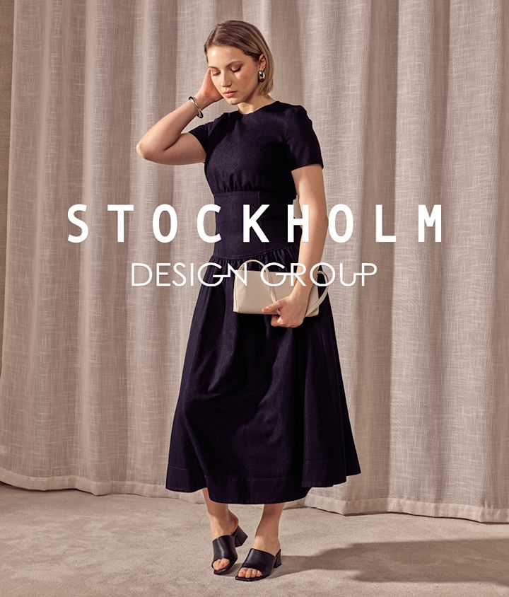 Kvinna i mörk klänning med svarta läder mules med klack, håller en beige clutch. Text: Stockholm Design Group.