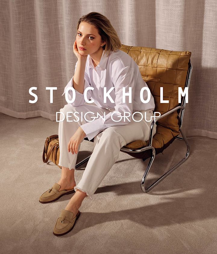 Kvinna sitter i läderfåtölj med beige loafers med spänne, vita byxor och vit skjorta.