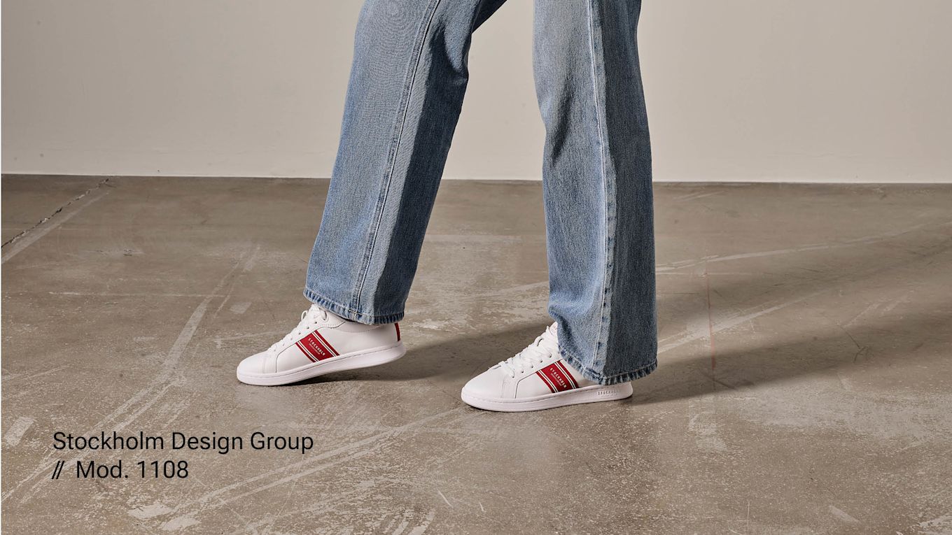 Hvite sneakers på fot med røde detaljer. Stockholm design Group.