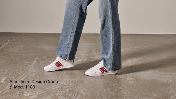 Hvite sneakers på fot med røde detaljer. Stockholm design Group.