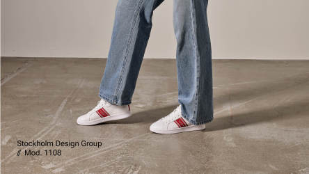 Vita sneakers på fot med röda detaljer från Stockholm Design Group.