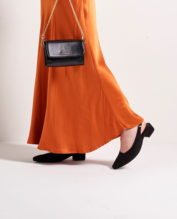 Svart vintervante med myk pelskant som holder en frostdekket växt i ett vinterlandskap.