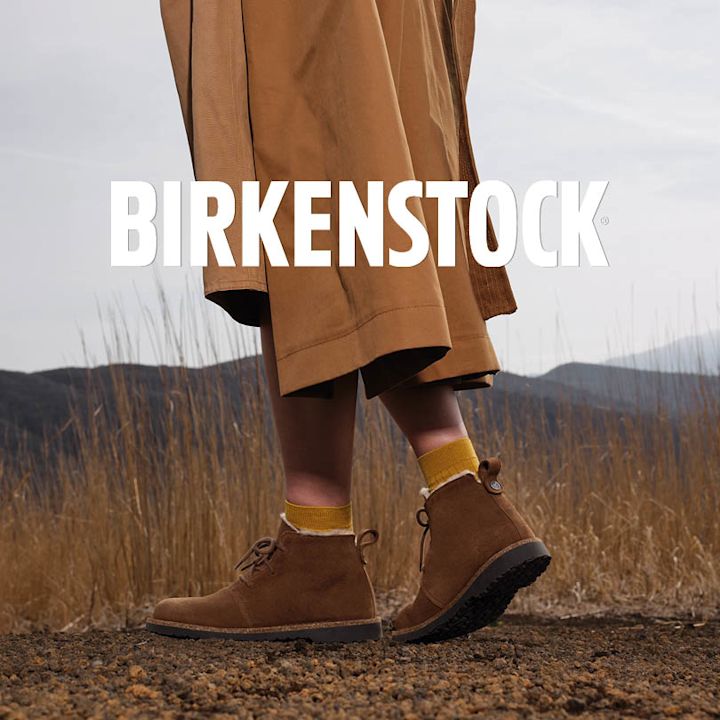 Birkenstock brune semsket ankelstøvletter med snøring og shearling-fôr, stylet med gule sokker utendørs.