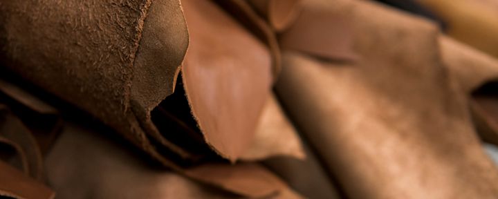 Rullar med brunt läder som ligger staplade i en verkstadsmiljö.