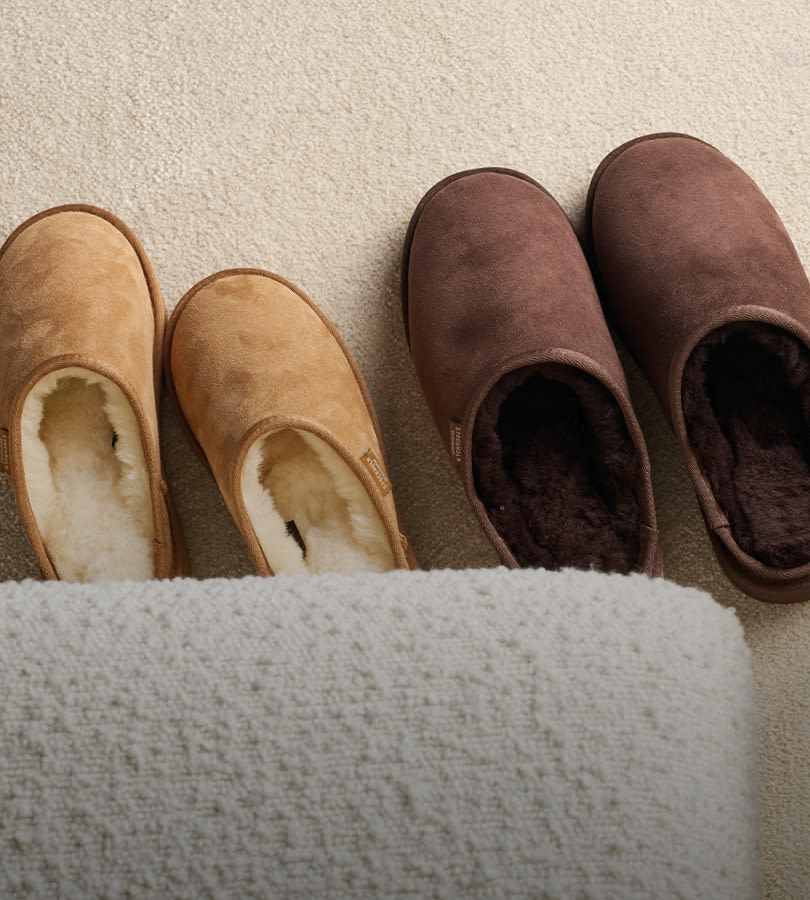 To par komfortable tøfler i semsket skinn - lysebrune med lys innside og mørkebrune med mørk innside på beige teppe.