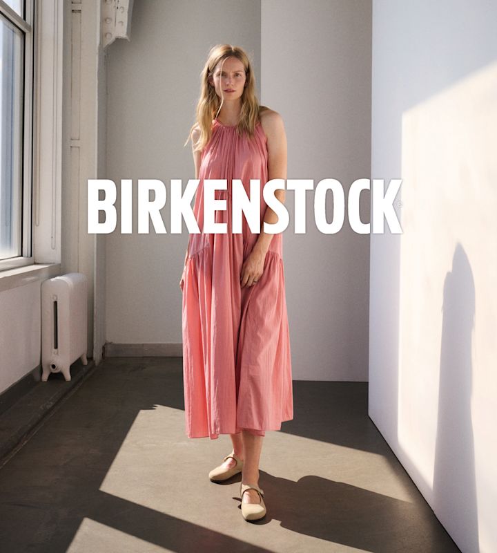 Kvinne i rosa sommerkjole med beige Birkenstock-ballerinasko med stropp over vristen.