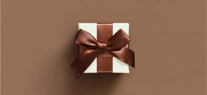 liten vit presentförpackning med ett brunt band på brun bakgrund