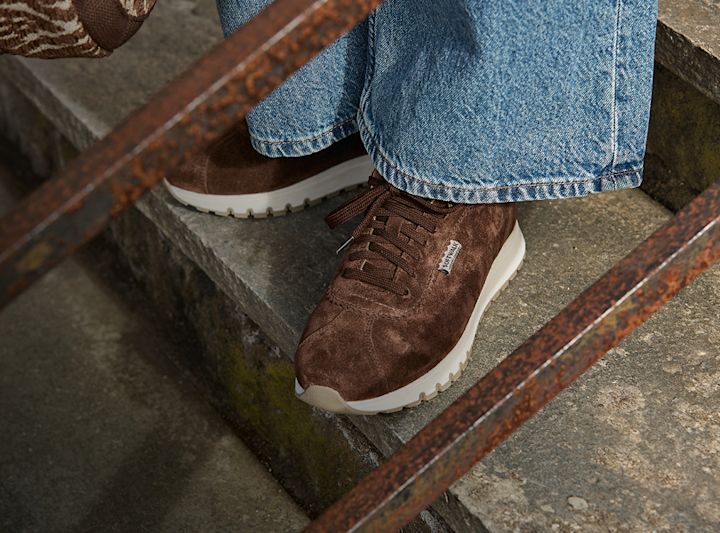 Bruna mocka sneakers med vit sula på stentrappa från Softwalk, burna med blå jeans.