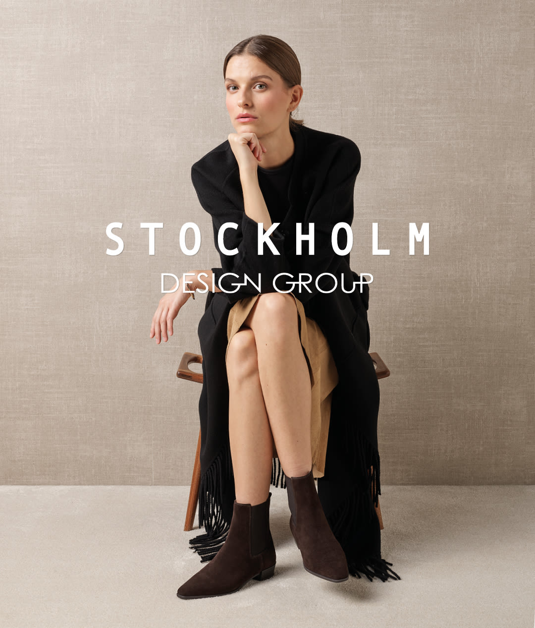 Modell med sorte ankelstøvletter i semsket skinn, med Stockholm Design Group-logo.