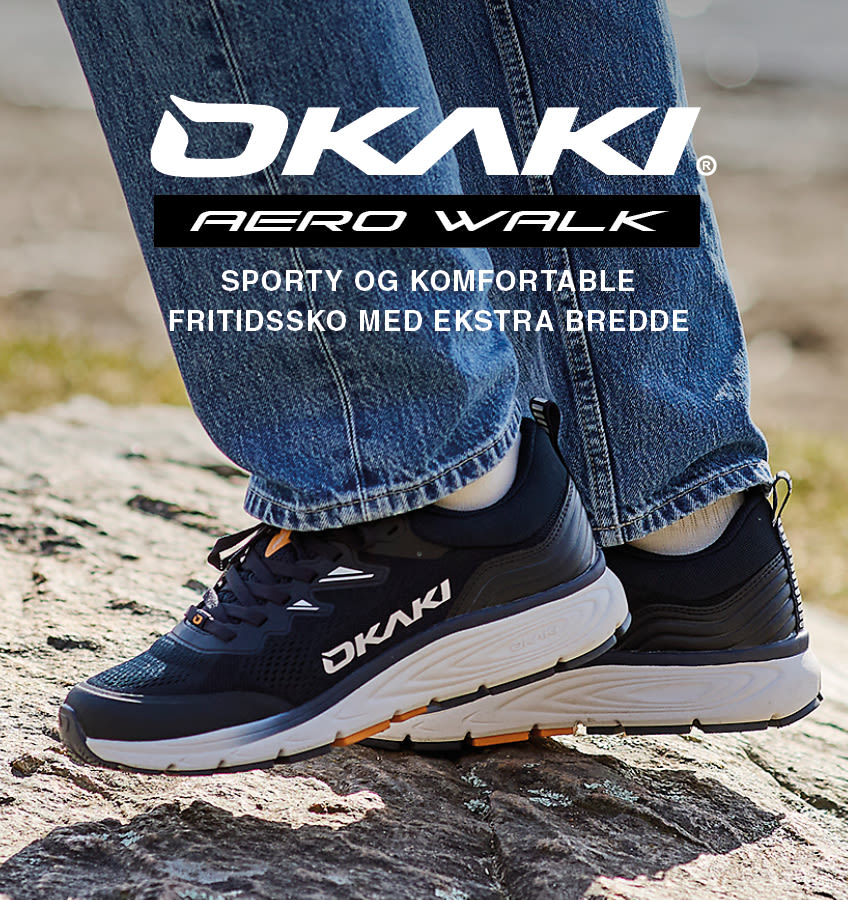 Svarte OKAKI Aero Walk fritidssko med hvit såle, vist på person med jeans. Sporty og komfortable med ekstra bredde.