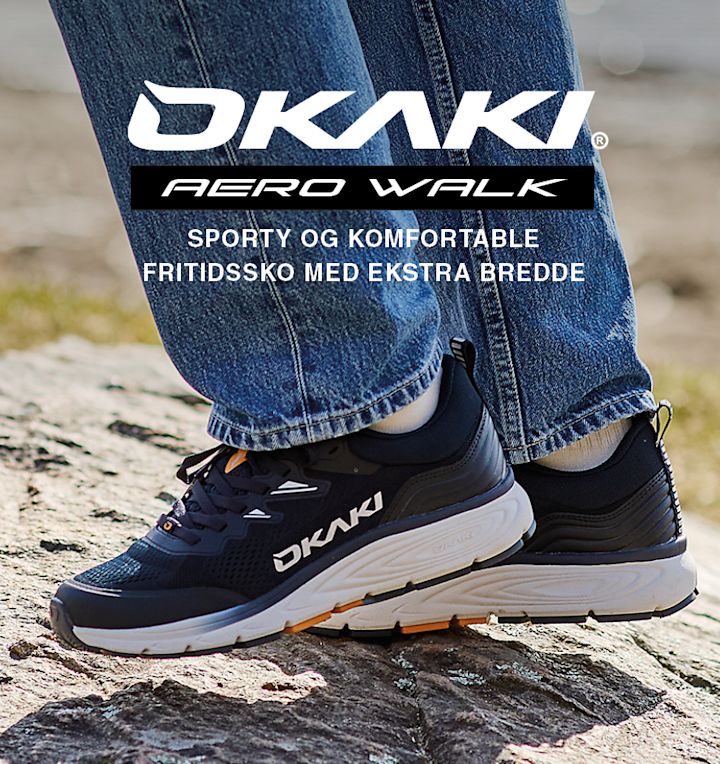 Svarte OKAKI Aero Walk fritidssko med hvit såle, vist på person med jeans. Sporty og komfortable med ekstra bredde.