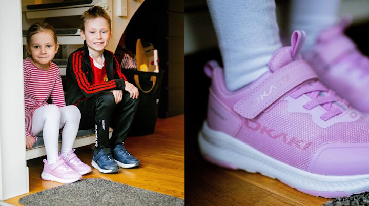 To barn sitter på en benk i gangen, jenta har på rosa OKAKI joggesko og gutten har på blå joggesko.
