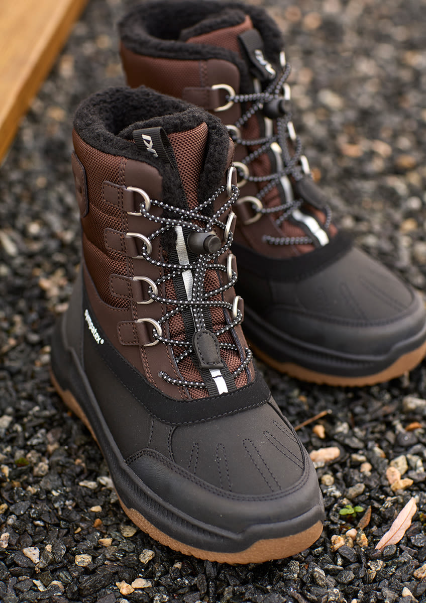 Bruna vinterkängor från Okaki med svart fodring, snörning med metallöglor och gummisula, designade för utomhusbruk på grusig mark.