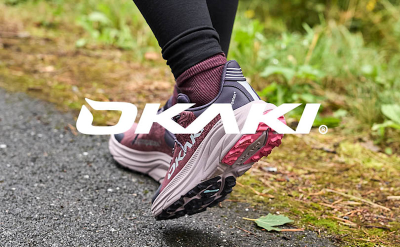 Okaki trailskor i lila och rosa med grova sulor på en grusväg i naturen.