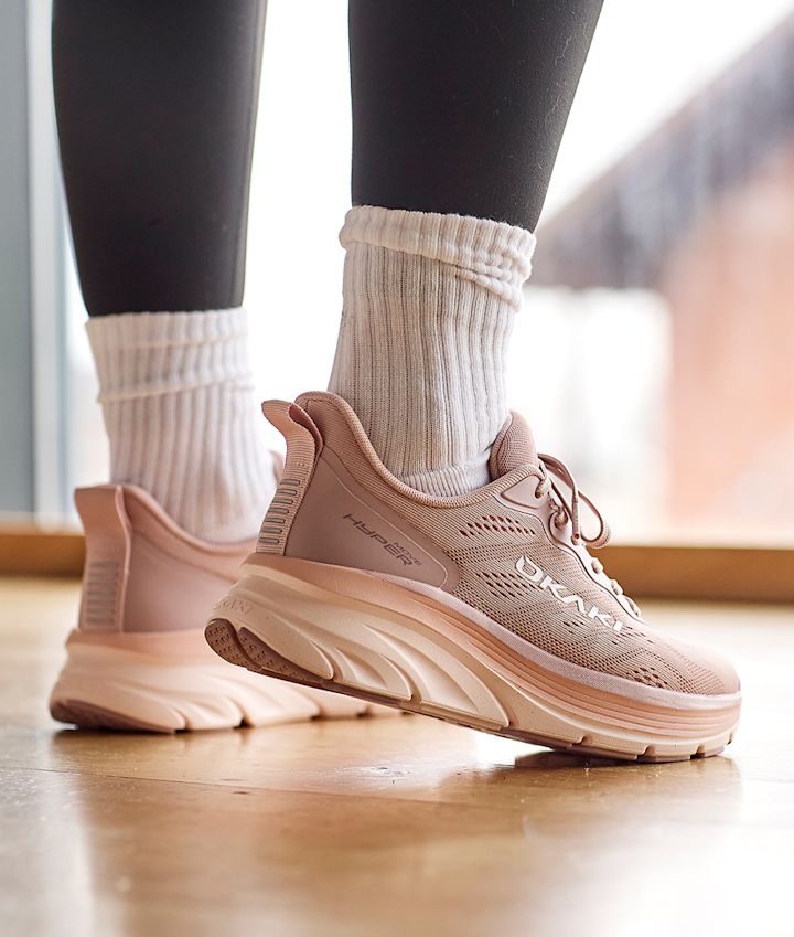 Rosa Okaki Hyper med tykk såle og mesh-overflate, brukt med svarte tights og hvite sokker på tregulv.