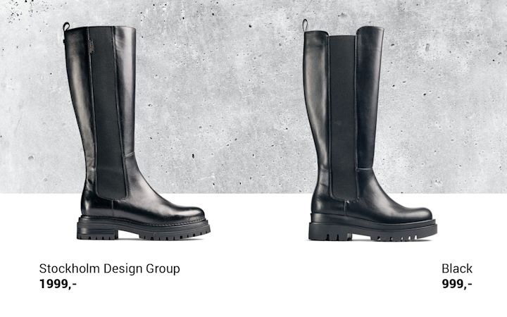 To svarte høye støvler med grov såle, plassert side om side mot en grå betongvegg, med pris og merkeinformasjon under.