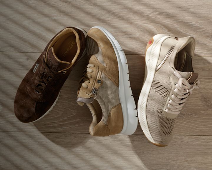 Tre par fritidssko i jordfarger: mørkebrune, beige og lysebeige med nettingdetaljer og hvite såler på tregulv.