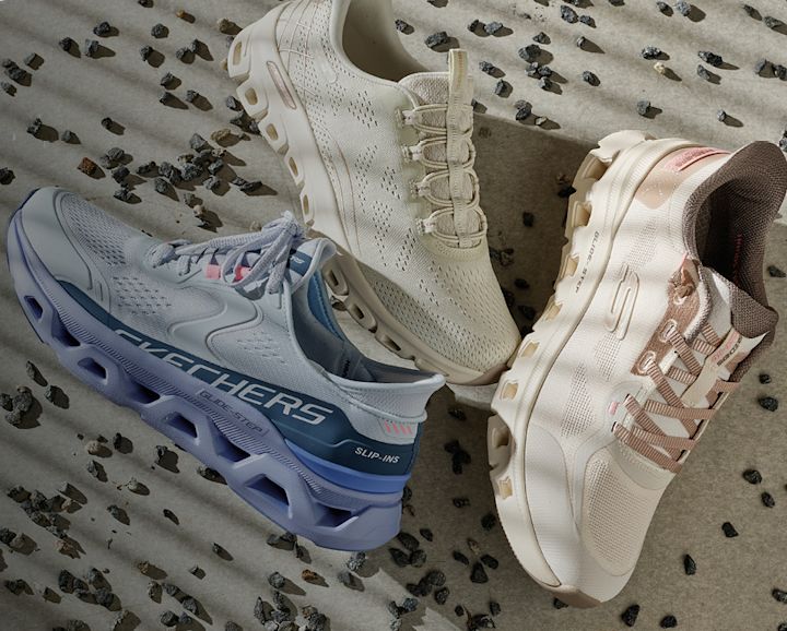 Tre Skechers joggesko på sand: lyseblå med luftsåle til venstre, kremhvite i midten og beige med rosa detaljer til høyre.