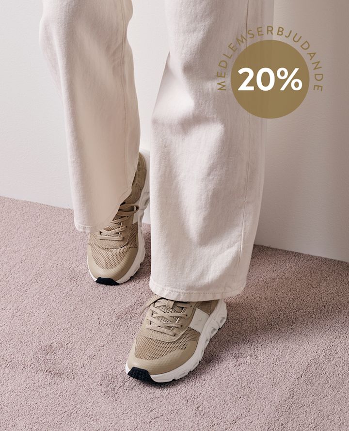 Beiga sneakers på fötter med ljusa byxor, står på en matta; cirkel med texten "MEDLEMSTILLBUD 20%".
