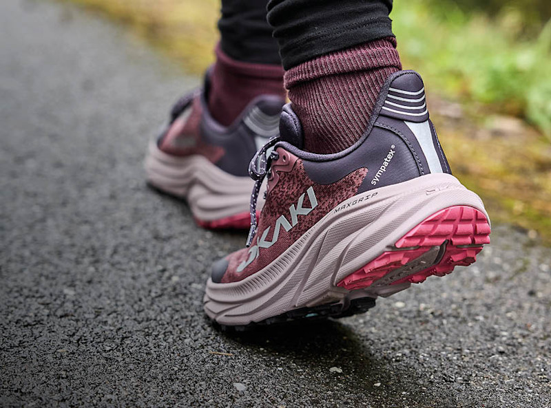 Okaki fritidsskor i lila och rosa med MaxGrip-sula och Sympatex-membran, burna med vinröda strumpor utomhus.