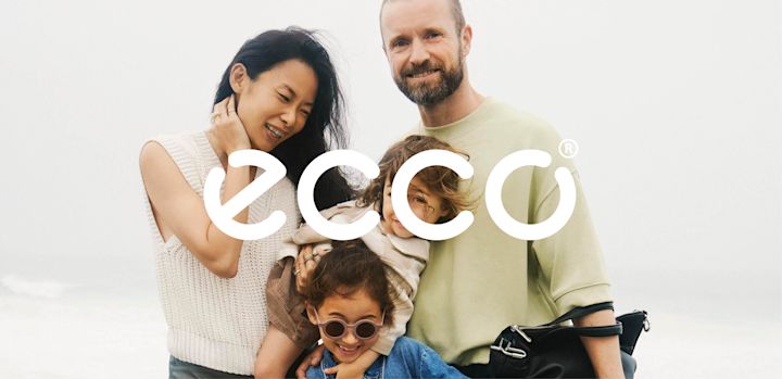 Logotyp: Ecco, familj med två vuxna och två barn som ler och kramar varandra utomhus i ljust, dimmigt väder.