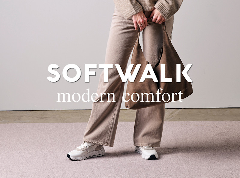 Person iförd beige byxor och vita sneakers håller en brun väska, med texten "SOFTWALK modern comfort" över motivet.