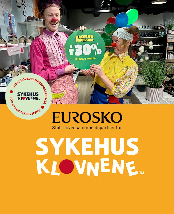 To klovner holder et grønt skilt med "30% på utvalgte barnesko" i en Eurosko-butikk med sko på hyller i bakgrunnen.
