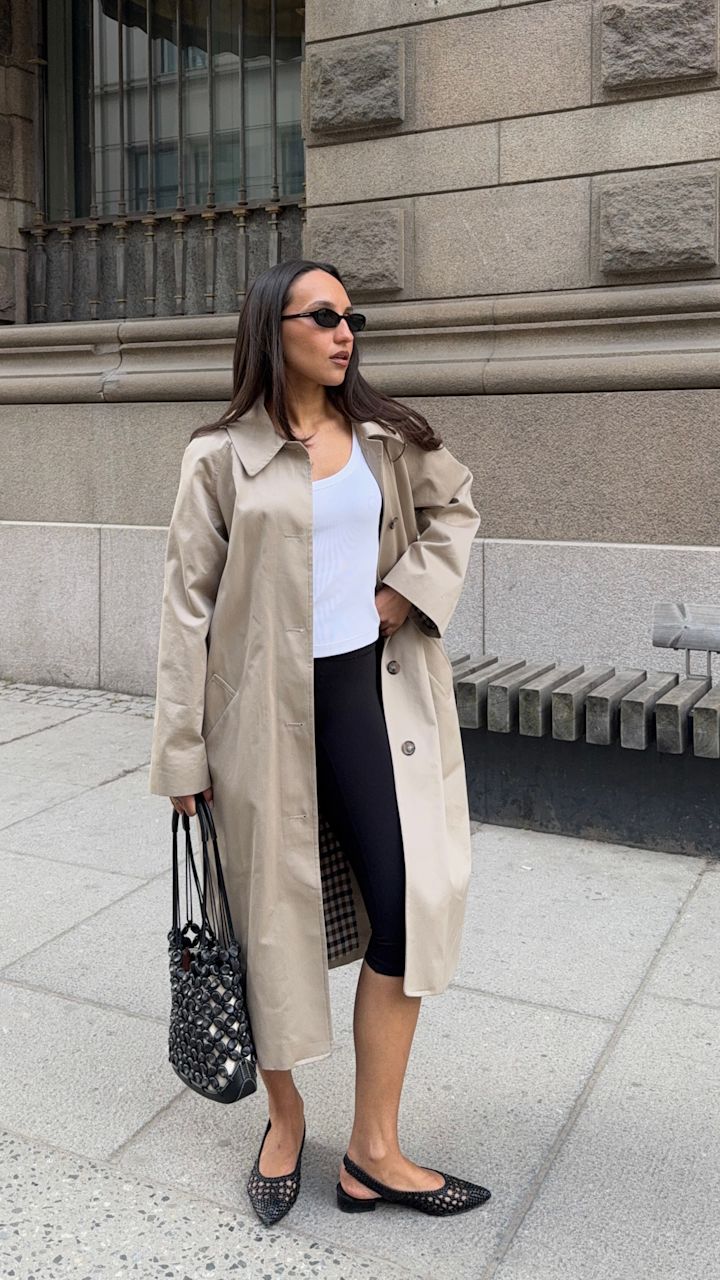 Influenser Ingrid Edvinsen i beige trenchcoat och svarta leggings bär svarta flätade slingback-ballerinaskor med spetsig tå från Stockholm Design Group.
