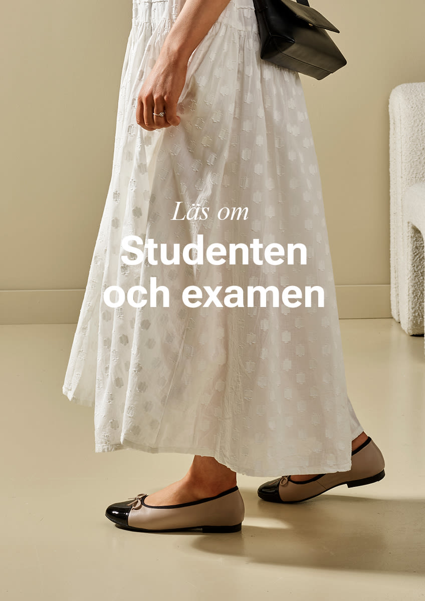 Person i vit mönstrad klänning bär eleganta beige ballerinaskor med svart tåhätta och rem, håller svart väska. Text: "Läs om STUDENTEN & EXAMEN".