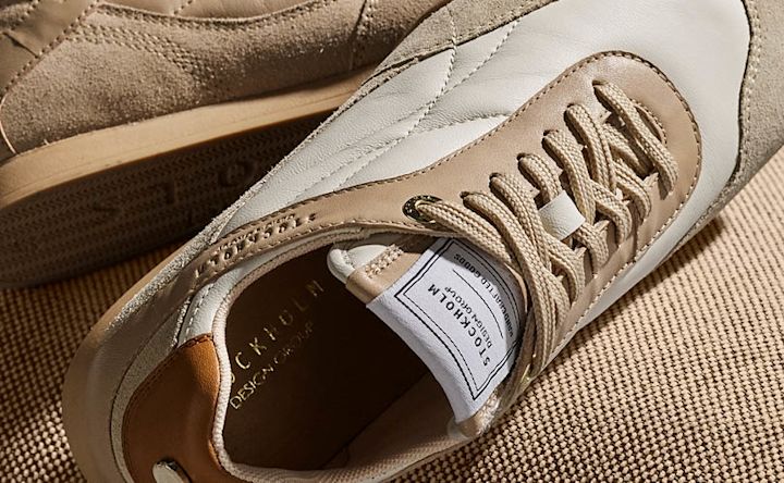 Beige og hvite retro sneakers i skinn og semsket skinn med beige snørebånd, merket Stockholm Design Group.