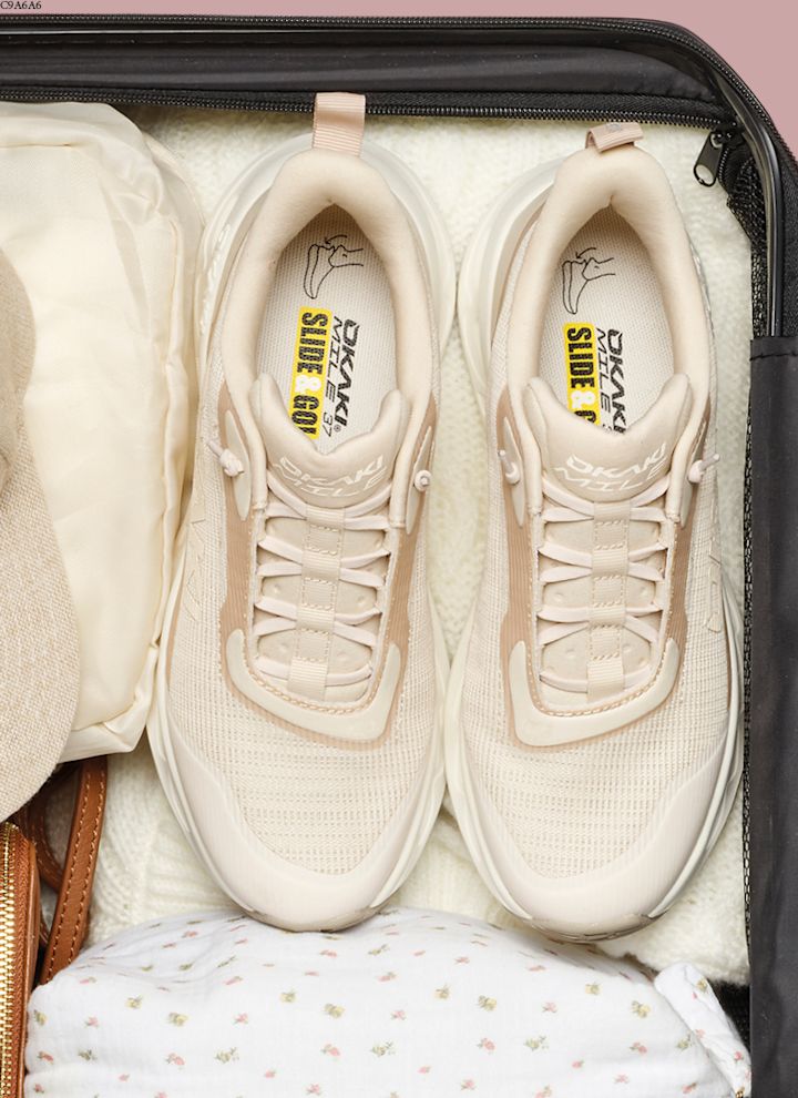 Beige sneakers pakket i en koffert sammen med klær, toalettmappe og en caps.
