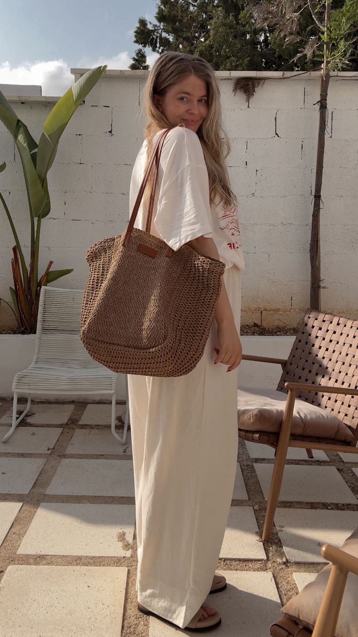 Influenser Anette Hovland med stor flettet stråveske på terrasse, iført enkle trendy, beige sandaler fra Stockholm Design Group.