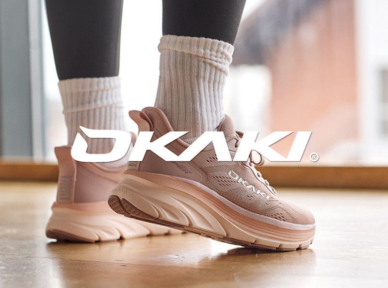 Rosa OKAKI fritidssko med tykk såle, brukt med svarte tights og hvite sokker på et tregulv.